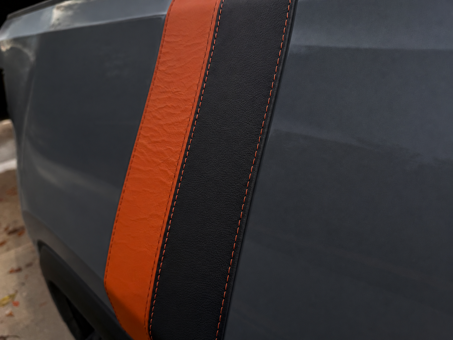 Close-up of cognac and black leather stripes with contrast stitching on a vehicle digitally recolored dark grey
